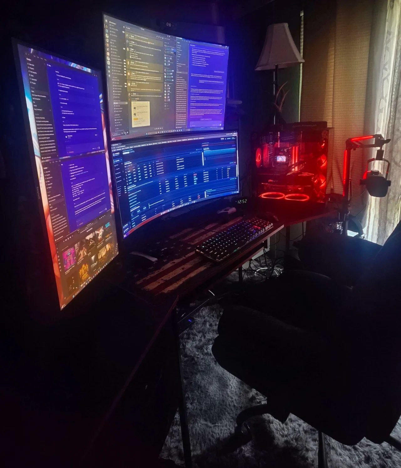Three-monitor workstation and PC tower illuminated in red, used for Downum Cyber development and command-center work.
